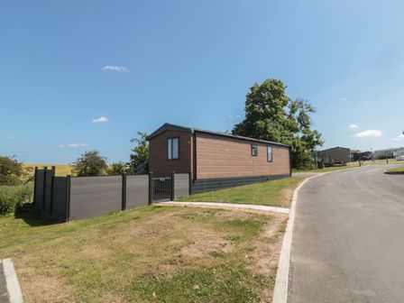 A mobile home with a fenced yard next to a paved road in a park