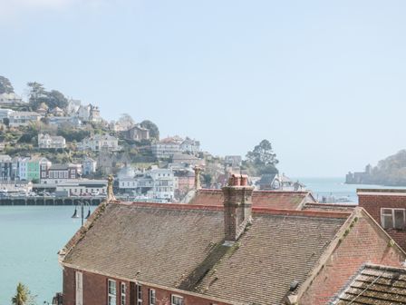 A view of rooftops with a body of water and a hillside with houses in the background at The Nest in Dartmouth