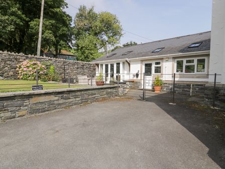 An outdoor area with a parking sign and flower bed at Pengwern Bach in Llanrwst
