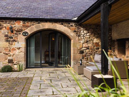 An outdoor area with a stone wall and seating at Fern Cottage in Akeld near Wooler