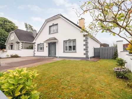 A detached house with a driveway and lawn with plants at 17 Clover Hill in Killorglin County Kerry