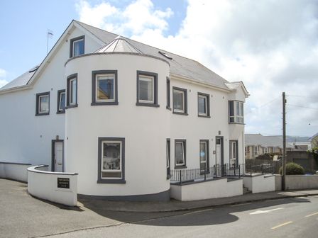 A white building with rounded corner and multiple windows at Apartment One in Duncannon County Wexford