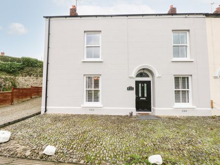 Front view of a white house with cobblestone driveway and black door at The Old Bakery in Milton Tenby