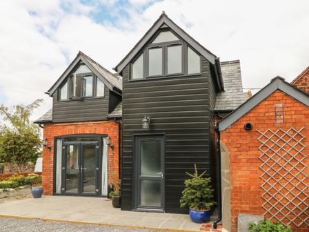 Exterior view of a brick and black cladded house with large windows and potted plants at Hill Coach House in Watchet