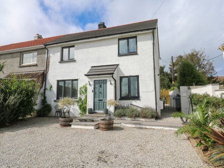 A semi detached house with a gravel driveway and potted plants at Cinders Loft in Illogan