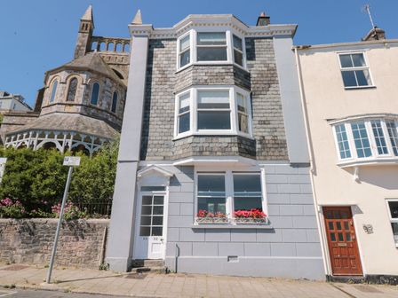 A street view of a building with bay windows and flowers on the window ledge at Flat 1 32 Newcomen Road in Dartmouth