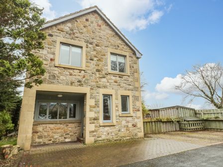 The exterior of a two story stone house with windows and a driveway at Ridley Lodge in West Thirston felton