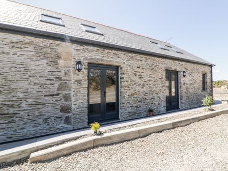 Exterior view of a stone house with slate roof and black framed doors and windows at The Cornstore in Helland near Bodmin