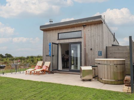 An outdoor area with a hot tub, seating and a grill at The Cadeleigh in Cadeleigh near Tiverton