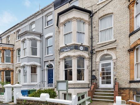 A row of terraced houses with bay windows and steps leading to front doors at Senna Rocks in Scarborough