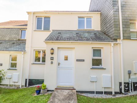 Front view of a two-story house with a white door and windows with small garden pots at Owls Roost in Pendra Loweth near Falmouth