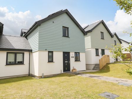 Two modern detached houses with light blue upper cladding and white lower walls with black framed windows and doors at 15 Parc Delfryn Benllech