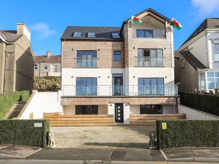 A modern multi-story house with balconies and Welsh flags at Bryn Min Manton Bach in Caernarfon