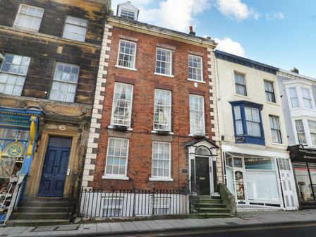 A street view of three and four story buildings with a red brick building in the center labeled Regent House in Scarborough