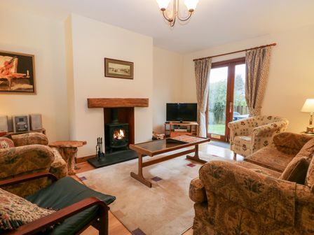 A living room with a wood burning stove television coffee table and a door leading outside at Friars Fold in Newby Bridge