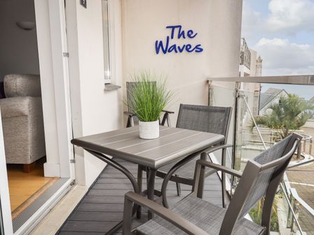 A balcony with a table and chairs and a potted plant on the table at The Waves in St Ives