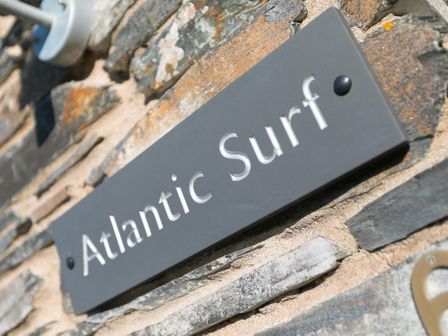 A close up of a sign reading Atlantic Surf mounted on a stone wall at Atlantic Surf in Carbis Bay
