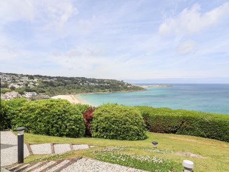 A coastal view with a sandy beach green bushes and blue sea at 1 and Only in Carbis Bay