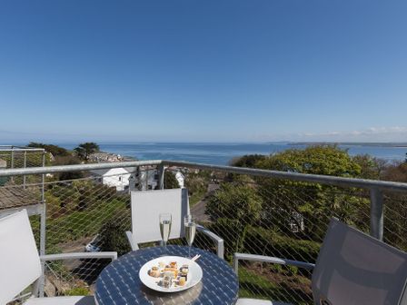 A balcony with a table set with sushi and drinks overlooking the sea at Belyars Penthouse in St Ives
