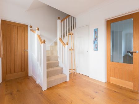 A hallway with carpeted stairs wooden floor a wooden door and a glass paneled door at Innisfree in Carbis Bay