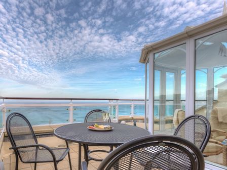 A patio with a round metal table and chairs overlooking the sea at Laurellie in Carbis Bay