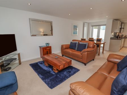 A living room with brown leather sofas a wooden coffee table and a blue rug at Moonsail in Carbis Bay
