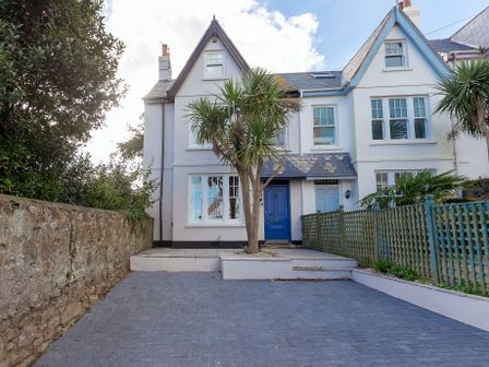 A front view of a house with blue door and windows a driveway and a fenced garden at Sea Dream in St Ives