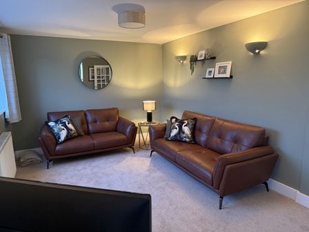 A living room with two brown sofas and a lamp at Sowena in Carbis Bay