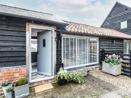 Front entrance of a house with an open blue door and flower pots outside at Freds Shed in Hereford