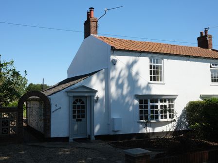 A white semi detached house with a tiled roof and a garden at Phloxhaven in Reedham