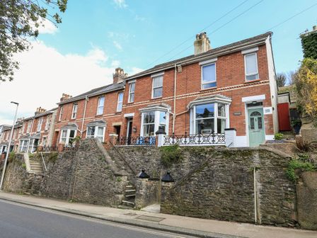 A row of brick terraced houses with steps leading up from the street at Hillside in Dartmouth