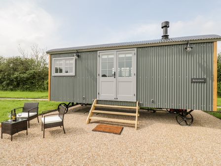 A green corrugated metal caravan with stairs and outdoor seating on gravel at Ridgeway in Uffington