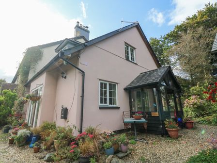 A house with a small porch and potted plants outside at Nattaden Fourwinds in Meldon near Okehampton