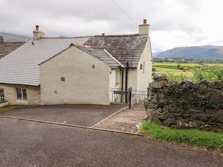 Exterior view of a house with a stone wall and driveway at Squirrel Cottage in Bassenthwaite
