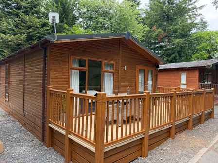 A wooden lodge with a deck and railing at Cherry Tree Lodge Calgarth 37, White Cross Bay near Windermere