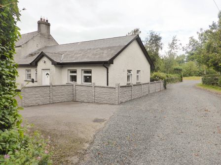 A single story house with a tiled roof and stone fence along a gravel driveway at Borahard Lodge in Newbridge County Kildare