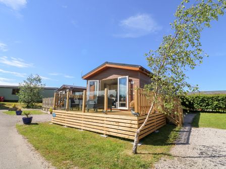 An exterior view of a wooden cabin with a patio area and outdoor furniture at Eden Lodge - Sherwood 21 in South Lakeland Leisure Village