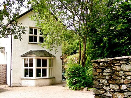 A white two-story house with a bay window and trees around at Stone Beck in Grasmere
