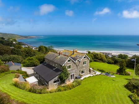 A stone house with a lawn and garden overlooking the ocean at Penmarth House in Coverack