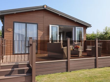 A porch with outdoor seating chairs and table in front of a brown wooden house at Bramblewick in Runswick Bay near Staithes