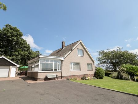 A house with a driveway a bench and a garage next to a lawn at Rose Bank in Belford