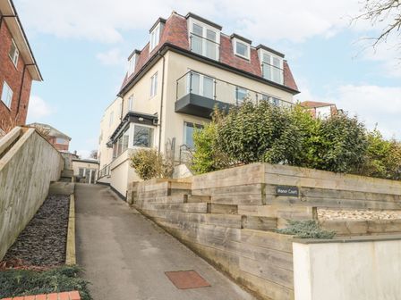 A multi-story residential building with a driveway and wooden retaining walls at Manor Court