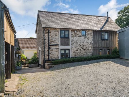 A stone and wood house with a tiled roof and gravel driveway at Hoglets in Exford