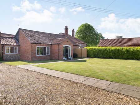 A brick house with a front lawn and a paved walkway at The Croft in Thompson near Watton
