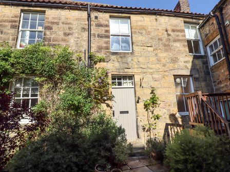 A stone exterior of a two story house with windows a door and plants at Beals Yard in Alnwick