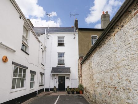 The exterior entrance of a white building with potted plants and stone wall at The Town House in Dorchester