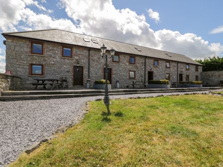 A stone building with picnic tables at Bwthyn Y Wennol in Dolwen near Abergele