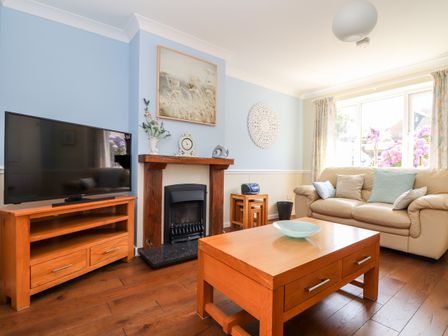 A living room with a beige sofa wooden coffee table television and fireplace at Dragonflies & Seahorses in Falmouth