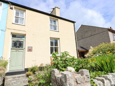Exterior of a two story house with a green door and garden at Silva in Penmon