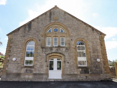 A stone building facade with arched windows and a white door at The Sigma Penthouse in Dyserth